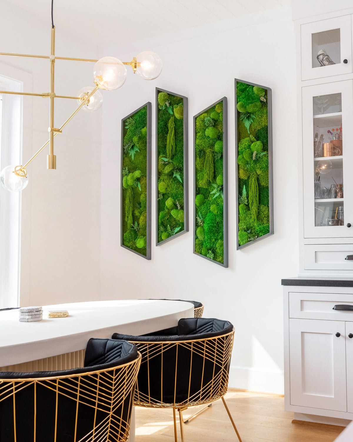 Three framed preserved moss panels on a kitchen wall in Ariana Madix's home beneath a gold chandelier