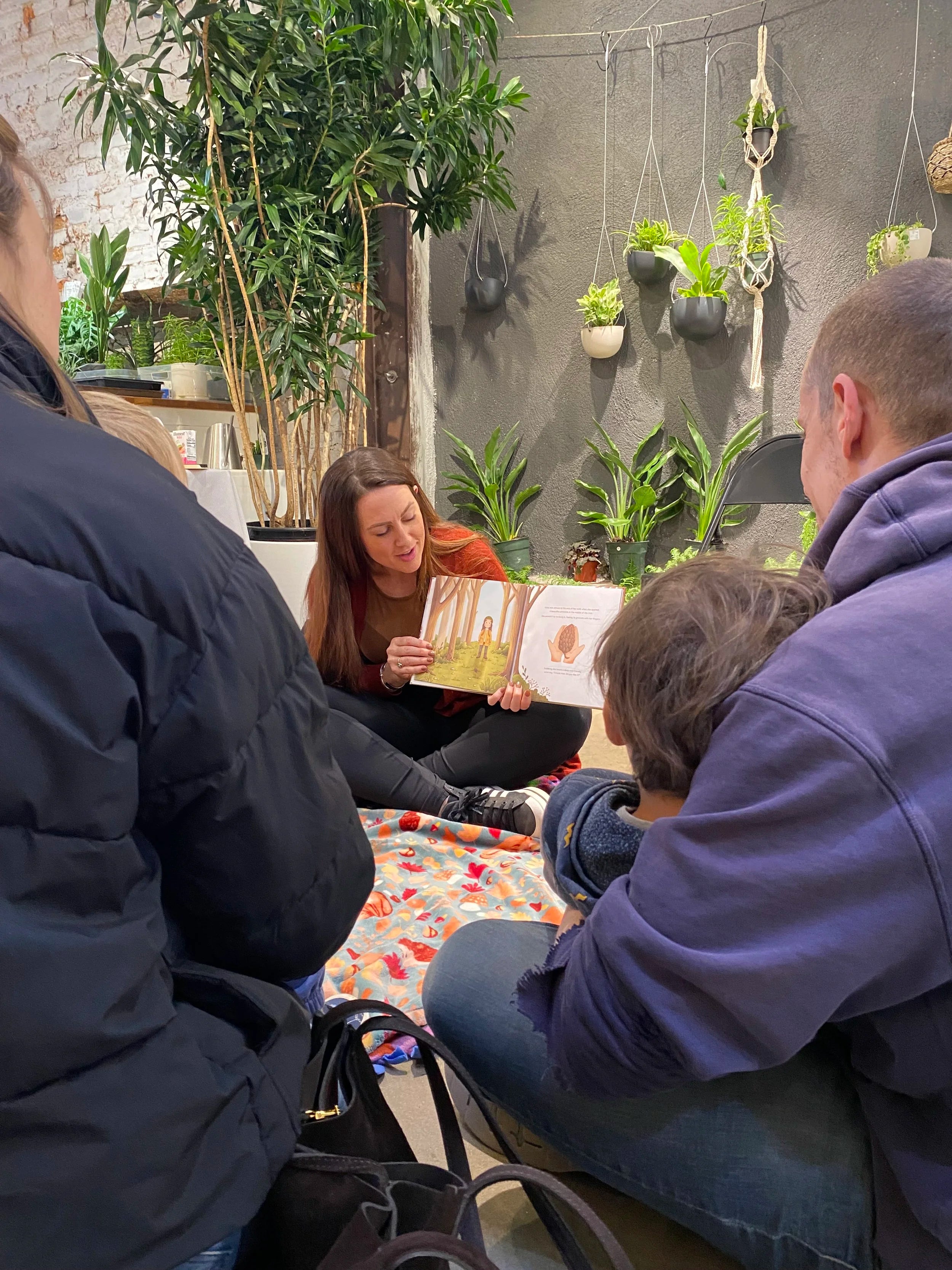 Kate Shooltz reading Kate the Earthling aloud to children at a plant shop story time