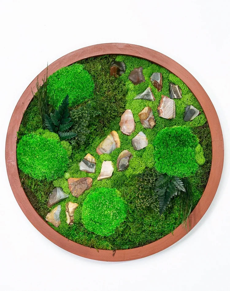 Round preserved moss art in a terracotta frame with a winding path of jasper stones
