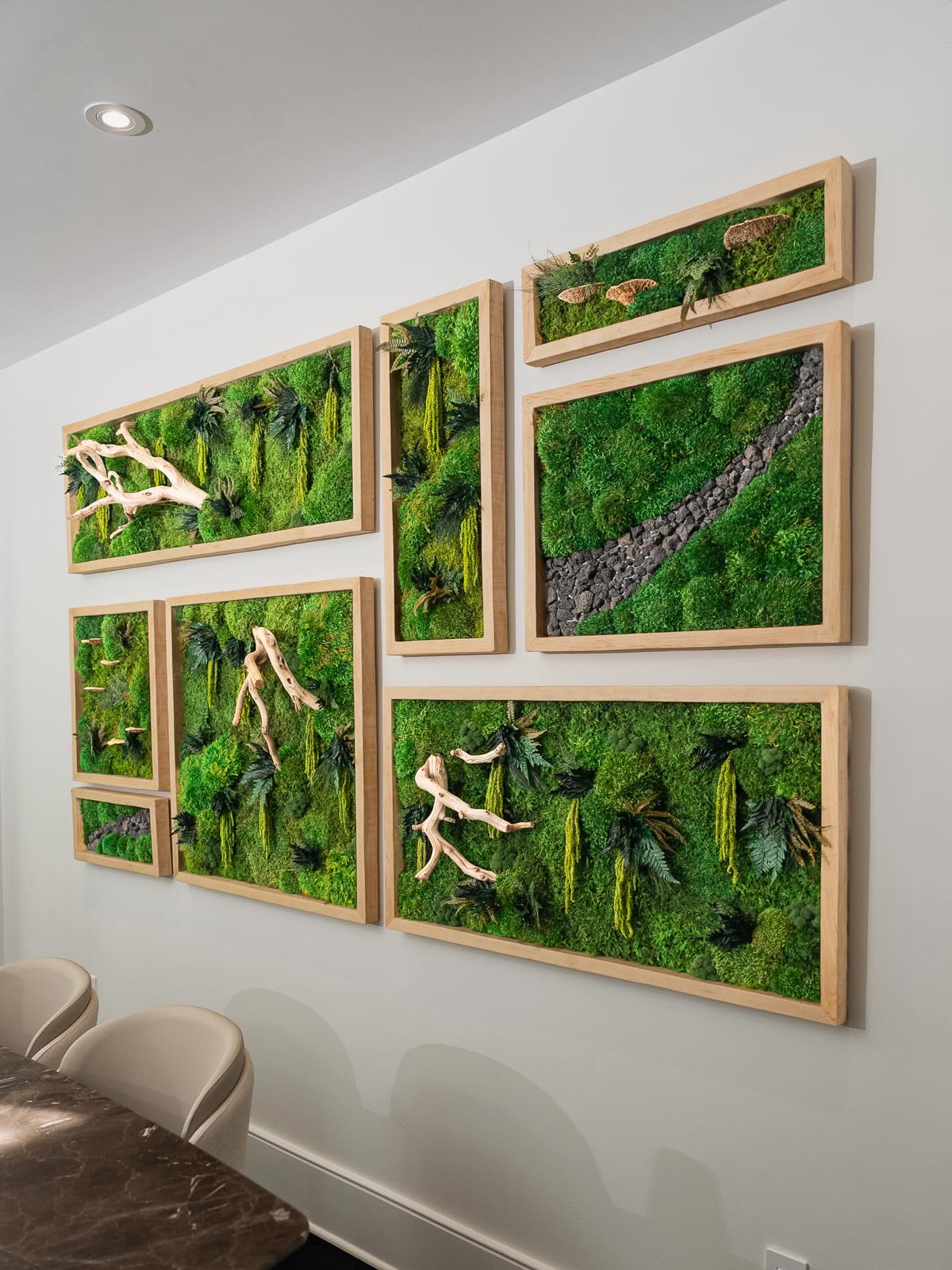 Large multi panel moss installation with driftwood and a stone river climbing a dining room wall