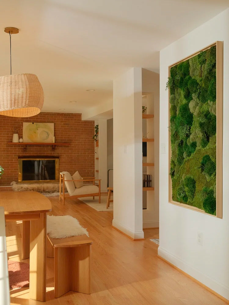 Tall wood framed moss panel with deep mounded texture on an entry wall, open living room and brick fireplace behind