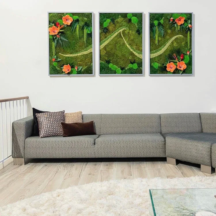 Three framed moss panels with a pale winding path and coral flowers hung above a grey sectional sofa