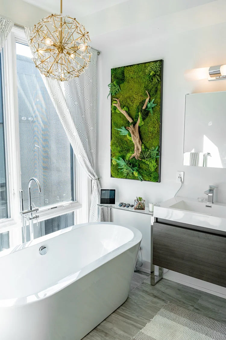 Tall preserved moss panel with driftwood and ferns on a white bathroom wall above a freestanding tub